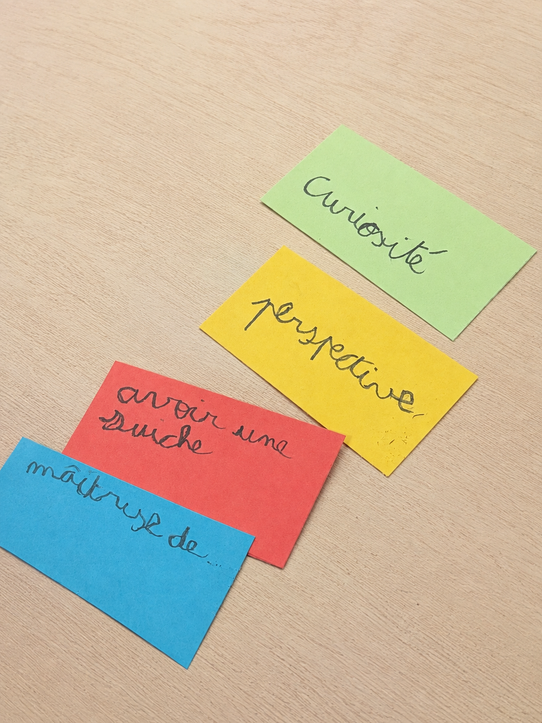 Colorful cards with student-written French words on a simple wood tabletop
